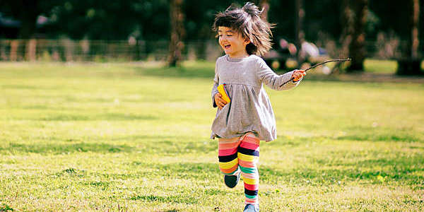Little girl running freely in a city park.