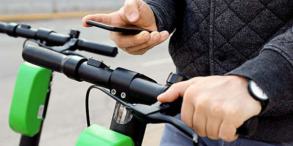 Close shot of cyclist holding the bike's handlebar in one hand and a smartphone in the other.
