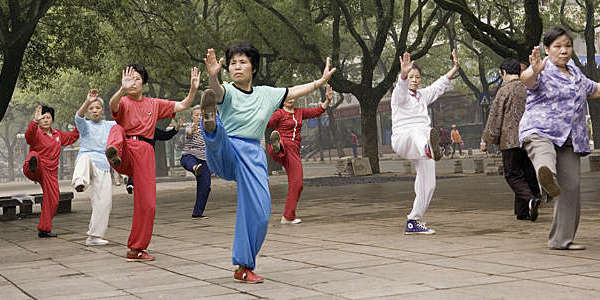 Group of Asian seniors practicing Tai Chi in the park.