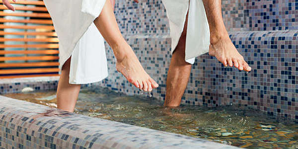 Close shot of a man and woman’s feet as they tread through the water at a hydrotherapy centre.