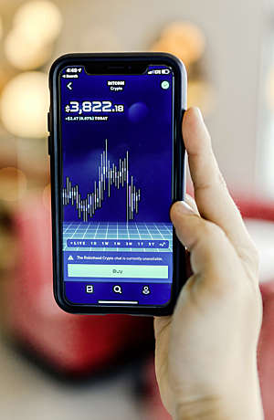 Hand holds a smartphone displaying the Bitcoin exchange rate.