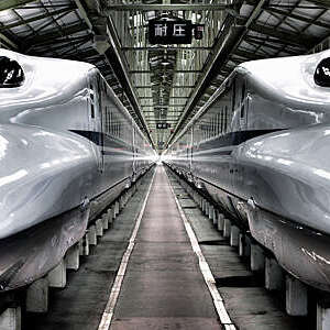 Vanishing perspective of two high-speed Japanese Shinkansen trains parked at a main station.