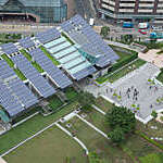 Aerial view of long strips of solar panels on the roof of a building. 