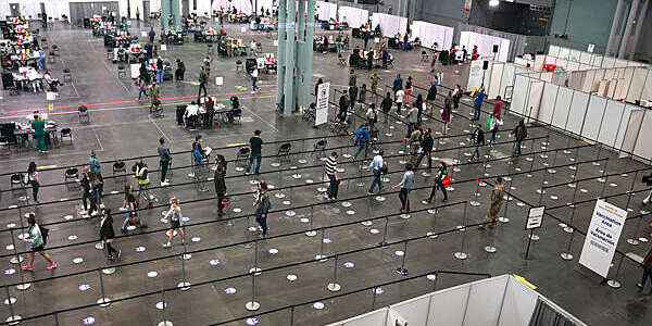 Plunging view of people lining up to receive the COVID-19 vaccine in a large hall of the Jacob K. Javits Convention Center, Manhattan, New York City.