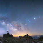 A man standing next to the Milky Way galaxy