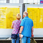 A senior couple is watching and reading timetable for local trains.