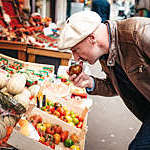 french man smelling on tomatoe at food stall in Paris street